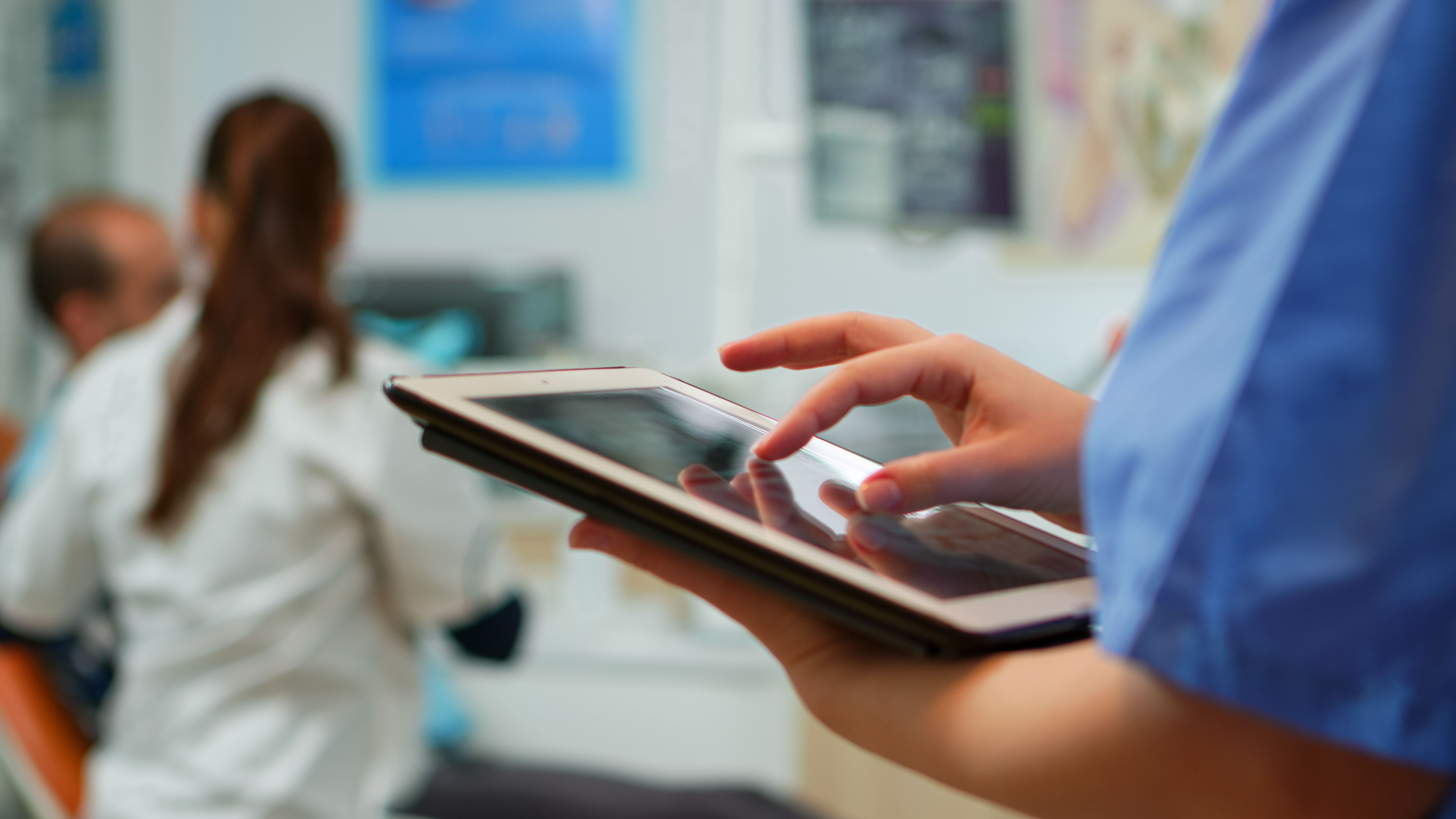 Healthcare professional holding tablet, reviewing remote monitoring data.